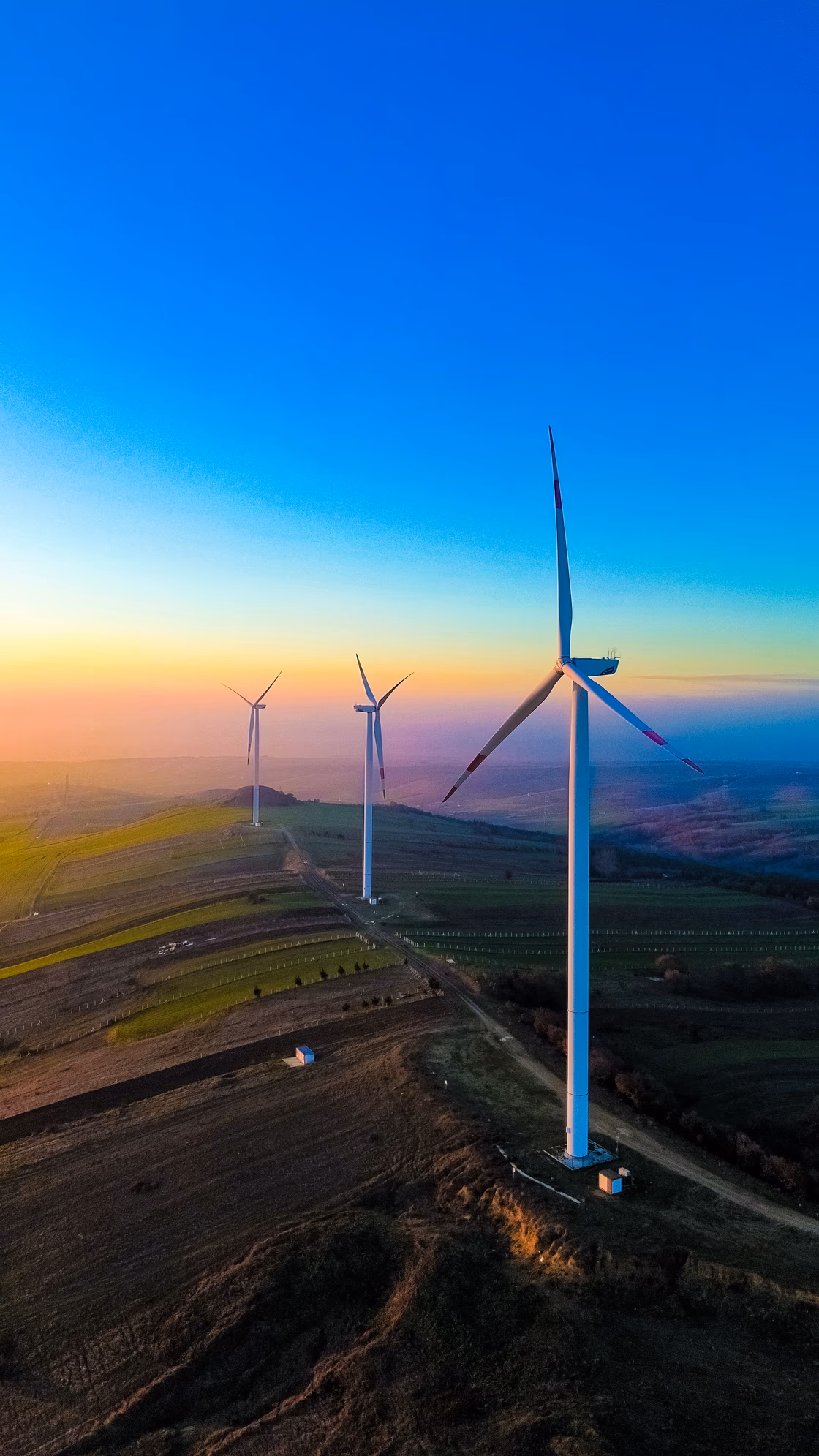 Wind turbines along a ridge at sunset, seen from the air